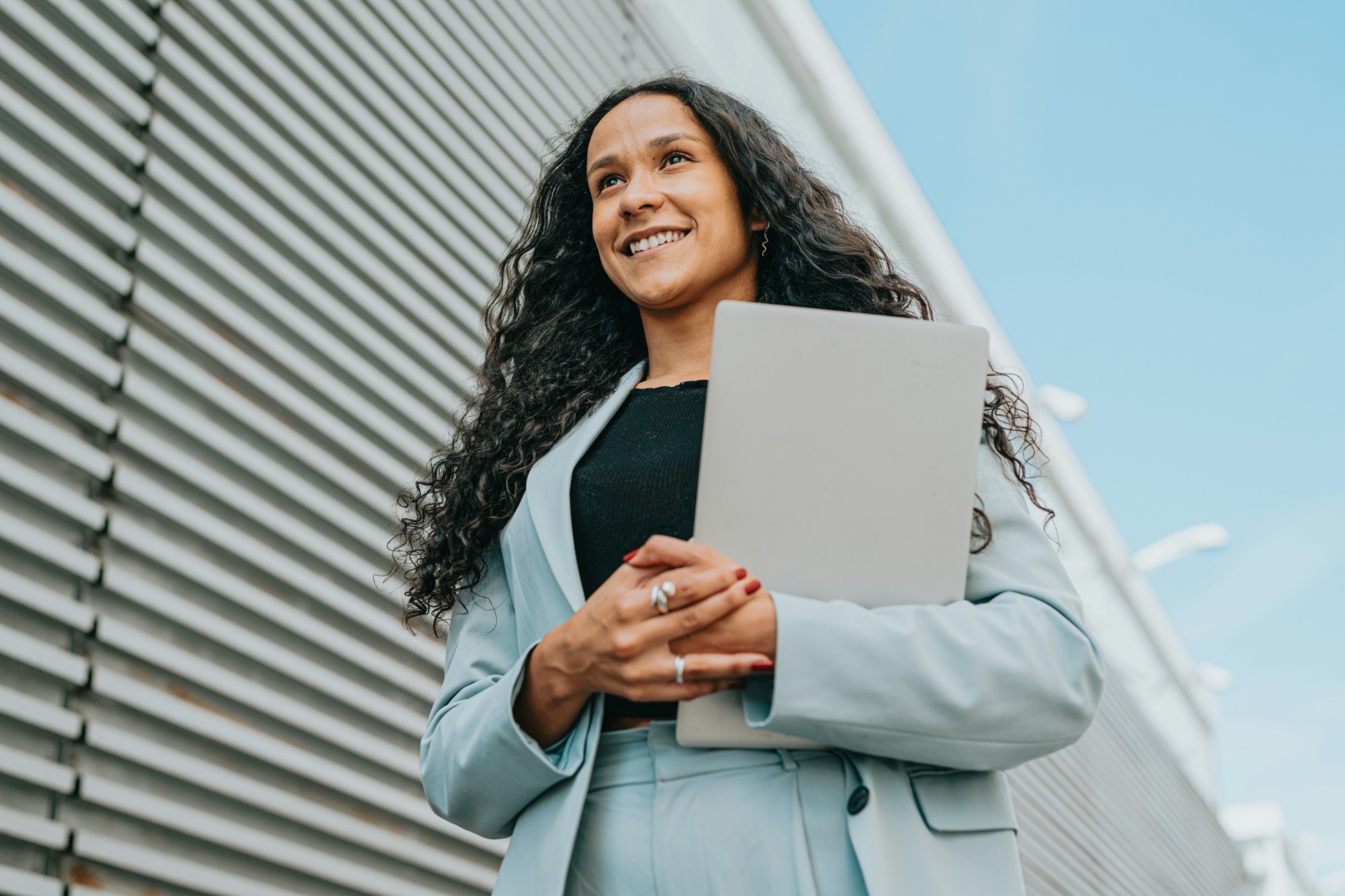 A smiling professional holding a laptop, looking ahead